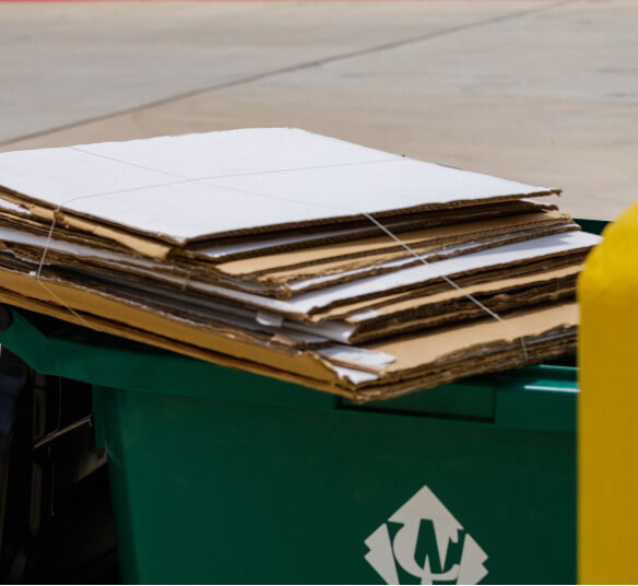 Stacked cardboard boxes on a recycling bin for commercial waste disposal services.
